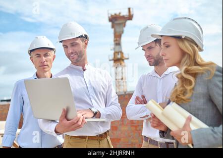 Construction engineer showing something to his colleagues on his laptop Stock Photo