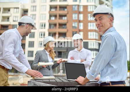 Worker standing among his three coworkers on the construction site Stock Photo