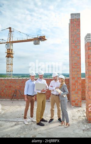 Concentrated young construction engineer surrounded by his colleagues outdoors Stock Photo