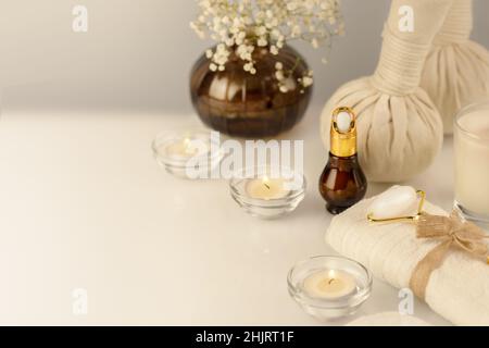 Spa relax massage procedure. Wellbeing cosmetology still life with spa accessories, serum, candles and towel on a white table. Wellness and skin care Stock Photo