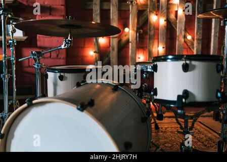 Drum set placed on carpet on stage decorated with shining garland for music concert in bar Stock Photo