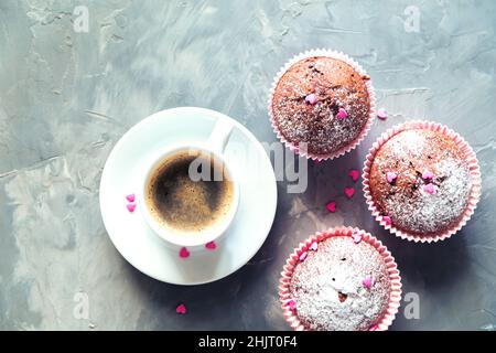 Cup of coffee, chocolate muffins and small hearts on a gray background. Food background, selective focus, flat lay. Stock Photo