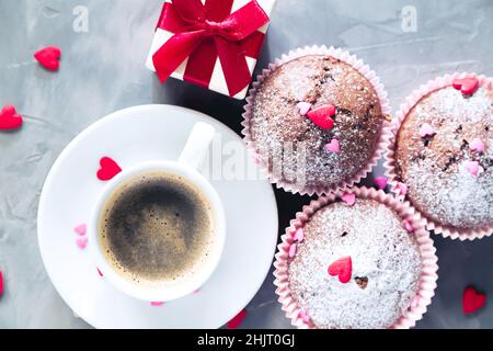 Cup of coffee, chocolate muffins and gift on gray background. The concept of a romantic morning, birthday or valentine's day. Stock Photo