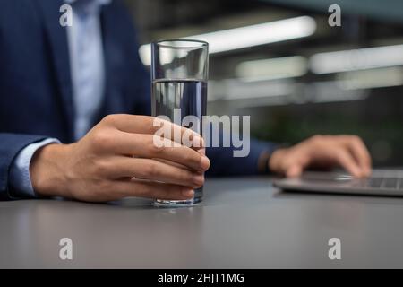 Unrecognizable manager drinking water while working on laptop Stock Photo