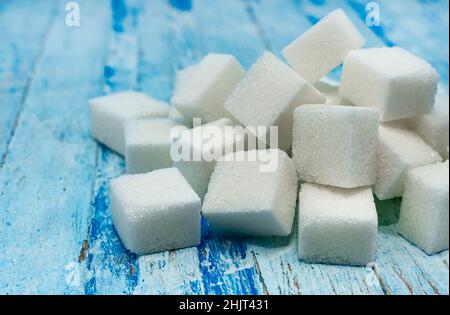 Sugar cubes. Refined sugar scattered on a wooden surface close-up Stock Photo