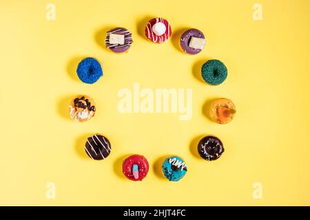 Colorful donuts or doughnuts in various shapes on yellow bright background. Colorful and happy image and concept. Stock Photo