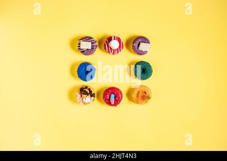 Colorful donuts or doughnuts in various shapes on yellow bright background. Colorful and happy image and concept. Stock Photo