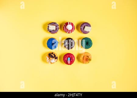 Colorful donuts or doughnuts in various shapes on yellow bright background. Colorful and happy image and concept. Stock Photo