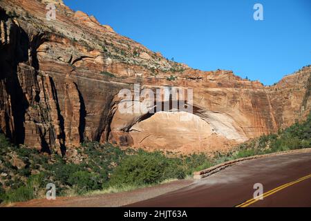 The arch shaped red mountain with the red paved road of Zion National Park in Utah Stock Photo