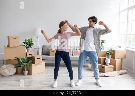Satisfied excited european young man in glasses and woman dancing in living room interior Stock Photo