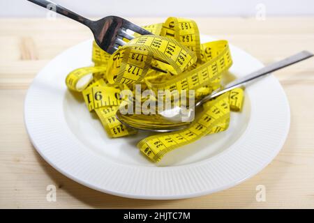 Tape measure like pasta on a plate with fork and spoon, diet concept to lose weight, selected focus, narrow depth of field Stock Photo