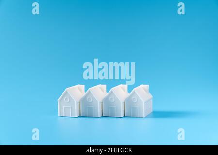 Miniature 3D printed model house on blue background Stock Photo