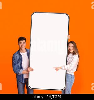 Excited couple pointing at white empty smartphone screen Stock Photo