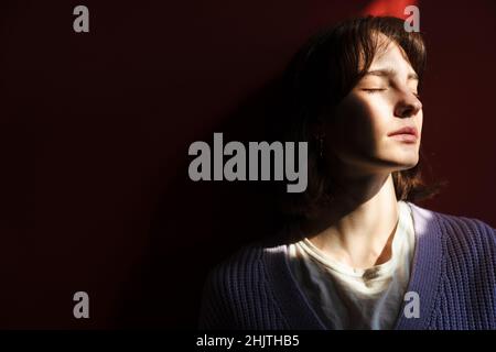 Young white woman posing with her eyes closed indoors Stock Photo