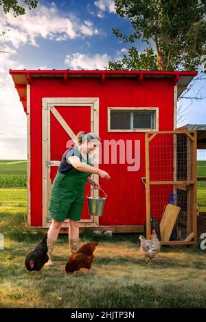 a woman feeding chickens on a farm Stock Photo