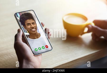 African american man talking to his friend online, using smartphone and drinking coffee in cafe, collage, closeup Stock Photo