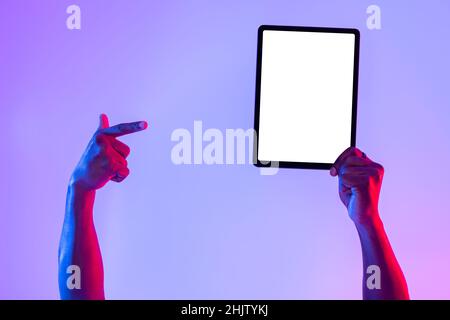 Tablet screen mockup. Cropped view of black man pointing at blank touch pad, recommending new app in neon light Stock Photo