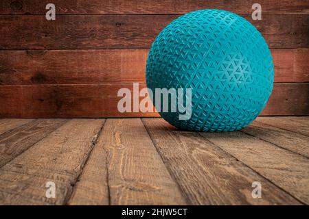heavy rubber slam ball filled with sand on a rustic wooden backgrouind, exercise and fitness concept Stock Photo