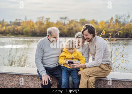 The boy shows the photo on the phone to his grandparents Stock Photo