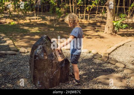Boy watching stone in the center of the green school,Bali Stock Photo