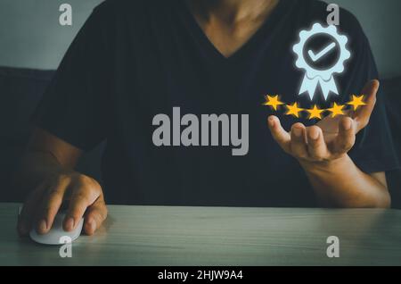 Businessman holding and showing the best quality assurance with golden five stars on virtual screen.Customer satisfaction and marketing survey rating Stock Photo