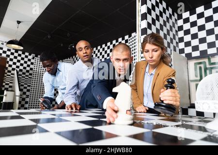 Businesspeople discussing near chessboard in quest room Stock Photo