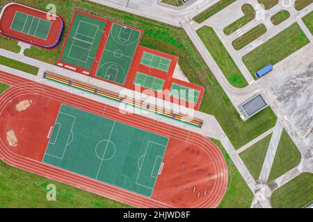 school sports ground with football stadium, jogging tracks around. basketball, volleyball, tennis courts. aerial photo, top view. Stock Photo