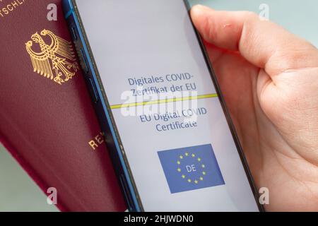 Berlin, Germany. 31st Jan, 2022. A person holds a smartphone (r) showing the EU's COVID digital certificate and a German passport. Anyone who wants to travel in the EU from February 1 will have to prepare for stricter rules. The validity of EU vaccination certificates will automatically expire nine months after basic immunization. In order to continue to travel more easily, a booster vaccination must have taken place. Credit: Fernando Gutierrez-Juarez/dpa-Zentralbild/dpa/Alamy Live News Stock Photo