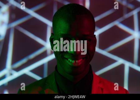Happy young African man with toothy smile looking at camera while standing against creative background Stock Photo