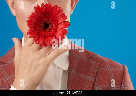 Cropped image of man in suit holding red flower in mouth Stock Photo