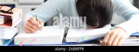Tired woman lies on folder with documents on table in office Stock Photo