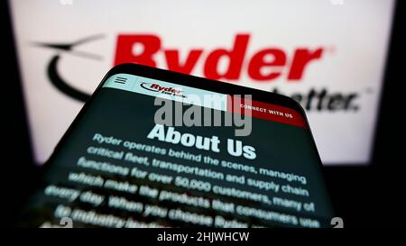 Mobile phone with webpage of American transportation company Ryder System Inc. on screen in front of logo. Focus on top-left of phone display. Stock Photo