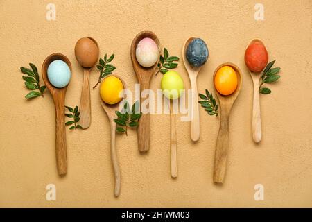 Spoons with painted Easter eggs on color background Stock Photo