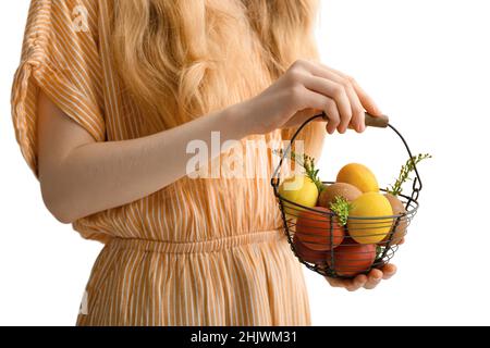 Woman holding basket with painted Easter eggs on light background Stock Photo