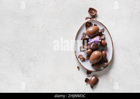 Plate with chocolate Easter eggs on light background Stock Photo