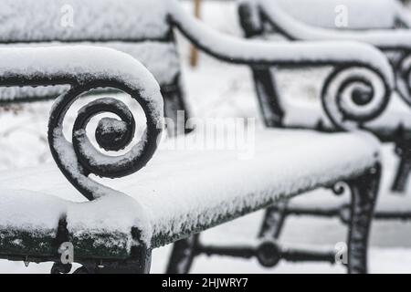 Old vintage bench in a park covered by the snow in winter, close up view Stock Photo