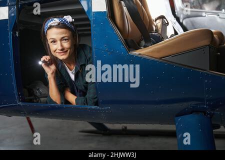 Woman mechanic with flashlight posing and looking at the photo camera Stock Photo