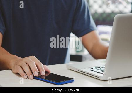 man working at computer desk pressing mobile phone Stock Photo