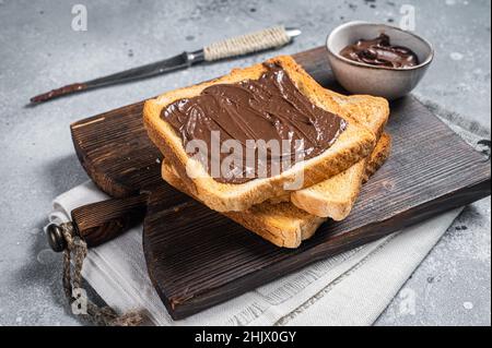 Toast with chocolate Hazelnut spread on wooden board. Gray background. Top view Stock Photo