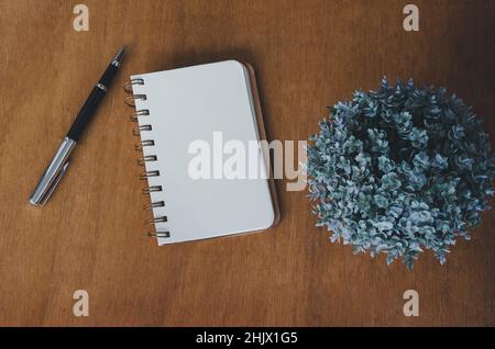 Notebook blank and pen and flower on vintage wood table background.Top view with copy space. Stock Photo