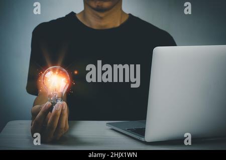 hand holding light bulb ideas Great inspiration and innovation on desk with computer laptop. Stock Photo