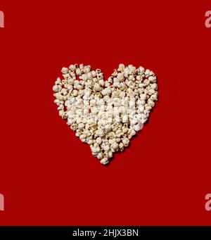Heart made of popcorn on red background Stock Photo