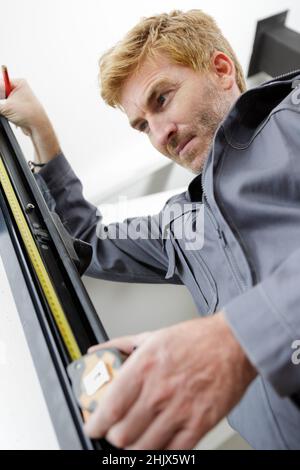 man measuring off metal bar in workshop Stock Photo