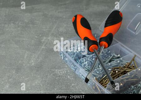 Box with screws and screwdrivers on gray textured background Stock Photo
