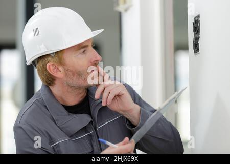 electrician looking at socket on wall Stock Photo