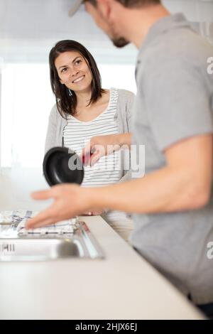 woman using plunger in blocked kitchen sink Stock Photo