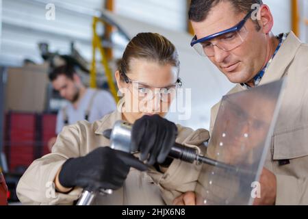 female trainee using machine on sheet metal Stock Photo