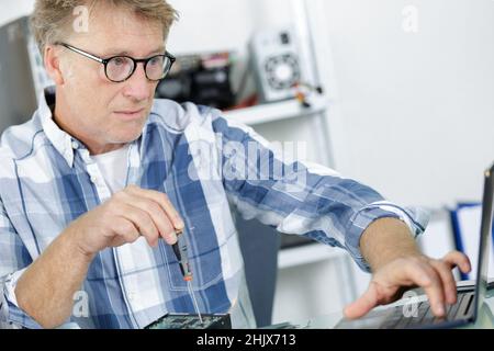 computer repairman installing new hard disk drive in laptop Stock Photo