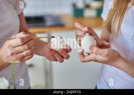 Hands with brush painting eggs for easter holiday. Stock Photo