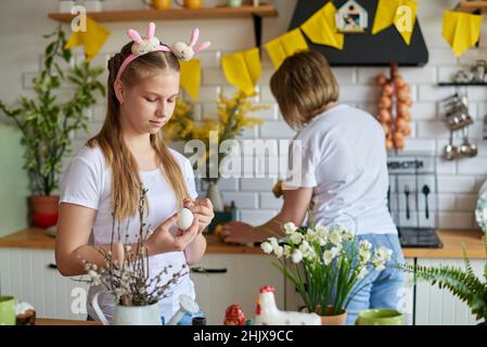 Mom and daughter are preparing for the Easter holiday in the kitchen. Stock Photo